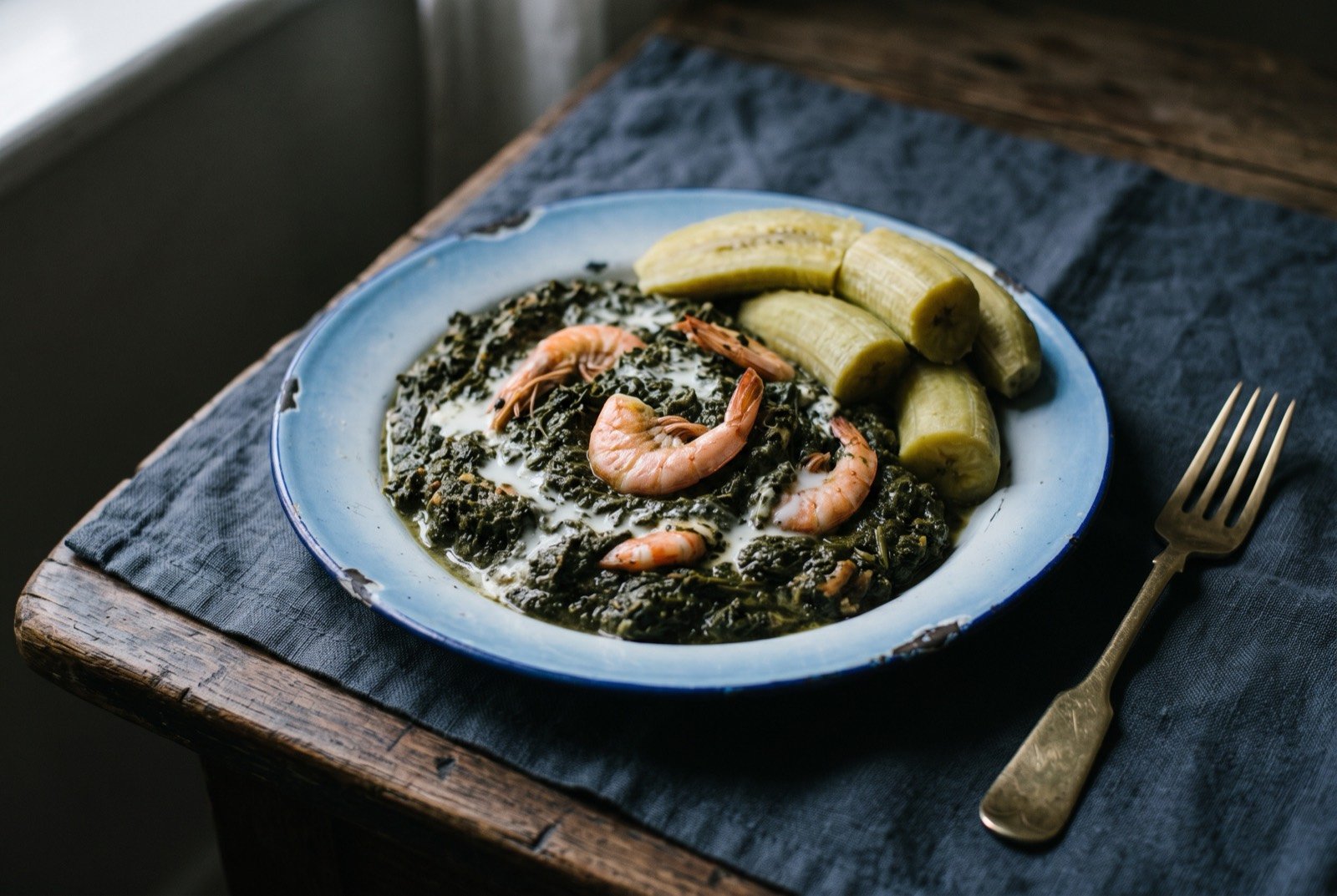 Mataba: a dense dark green mass of pounded cassava leaf, coarse and faintly glossy, loosened with ivory coconut milk that streaks pale through the green.