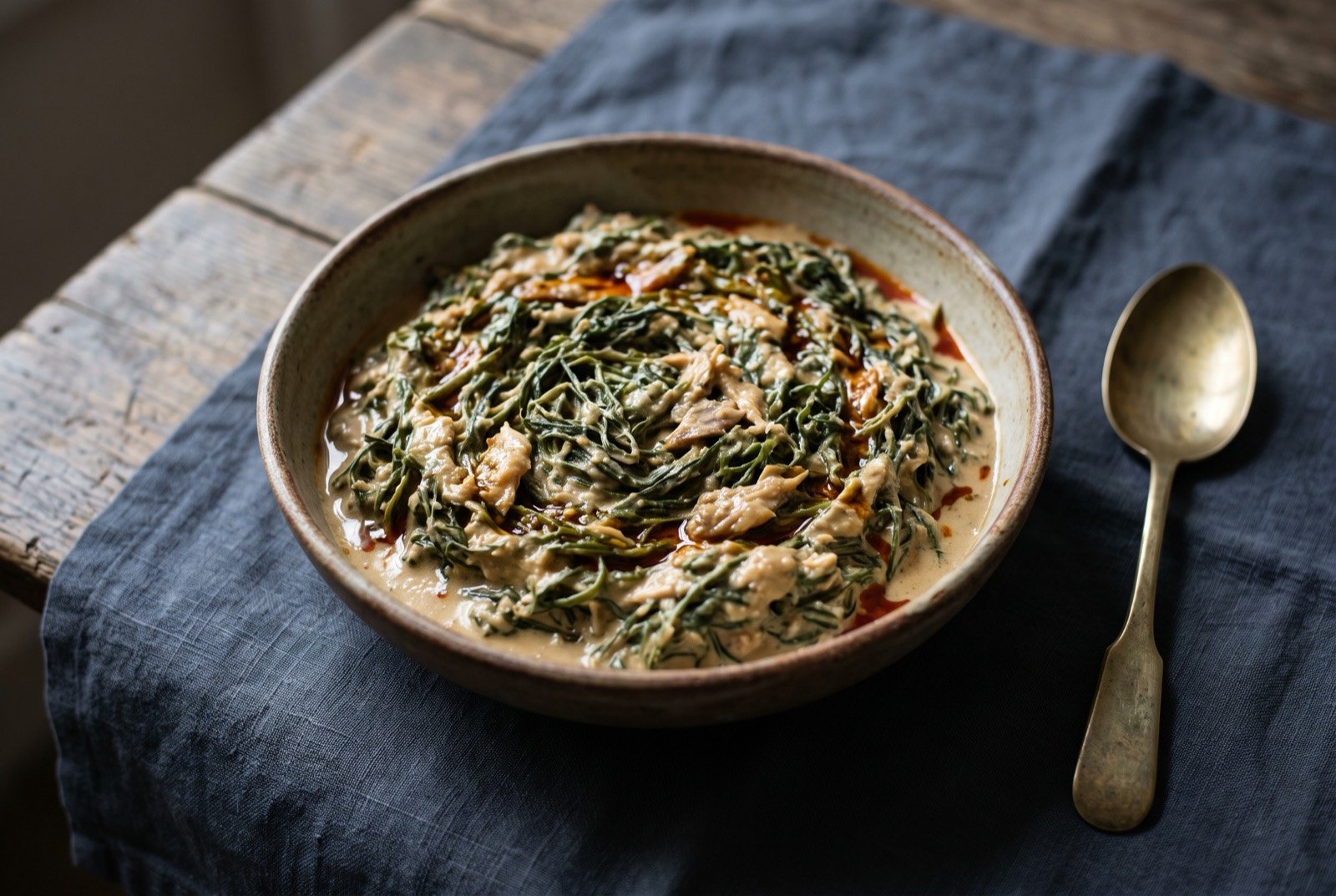 Okok: The same hair fine green vine shreds, this time bound in a thick pale beige groundnut sauce that coats rather than pools.