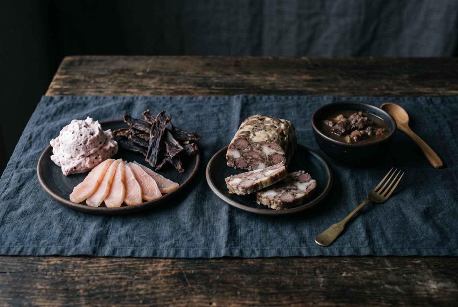 The Arctic and Subarctic table: a wide dark wooden table seen from above, a mound of whipped pale akutuq beside fanned translucent slices of frozen quaq.